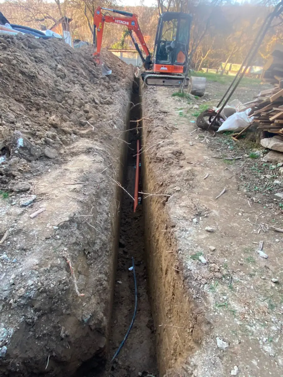 Șanț excavat cu conducte de utilități și miniexcavator
